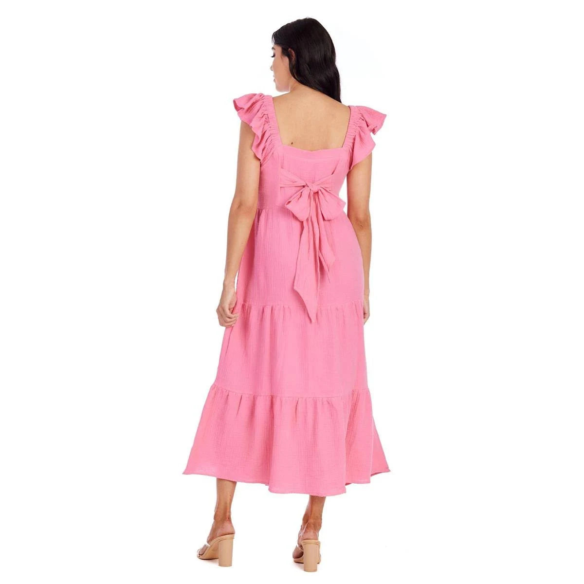 A pink Jane Maxi Dress featuring a ruffled design and a bow at the back. Available in sizes XS through XL.