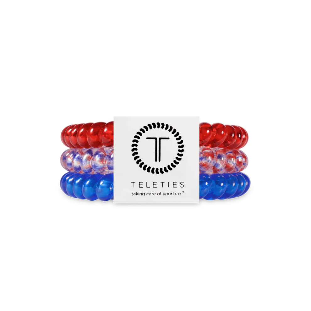 Three TELETIES Hair Ties—red, clear with blue, and blue—in branded white packaging. Available in small and large sizes.