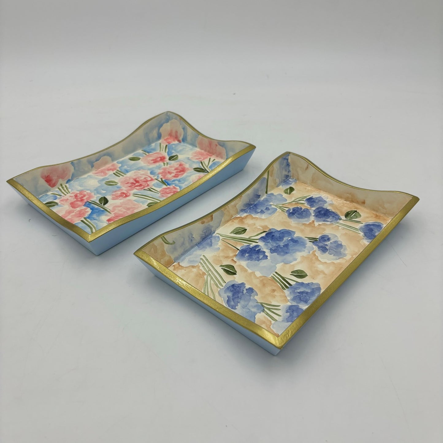 Handpainted wood trays with scalloped edges, one with pink flowers and the other with a blue floral pattern. Size: 5.75x8.75x1".