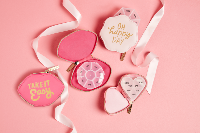 Three pink pill cases with zipper closures and gold accents. Sizes: Small, Medium, Large.