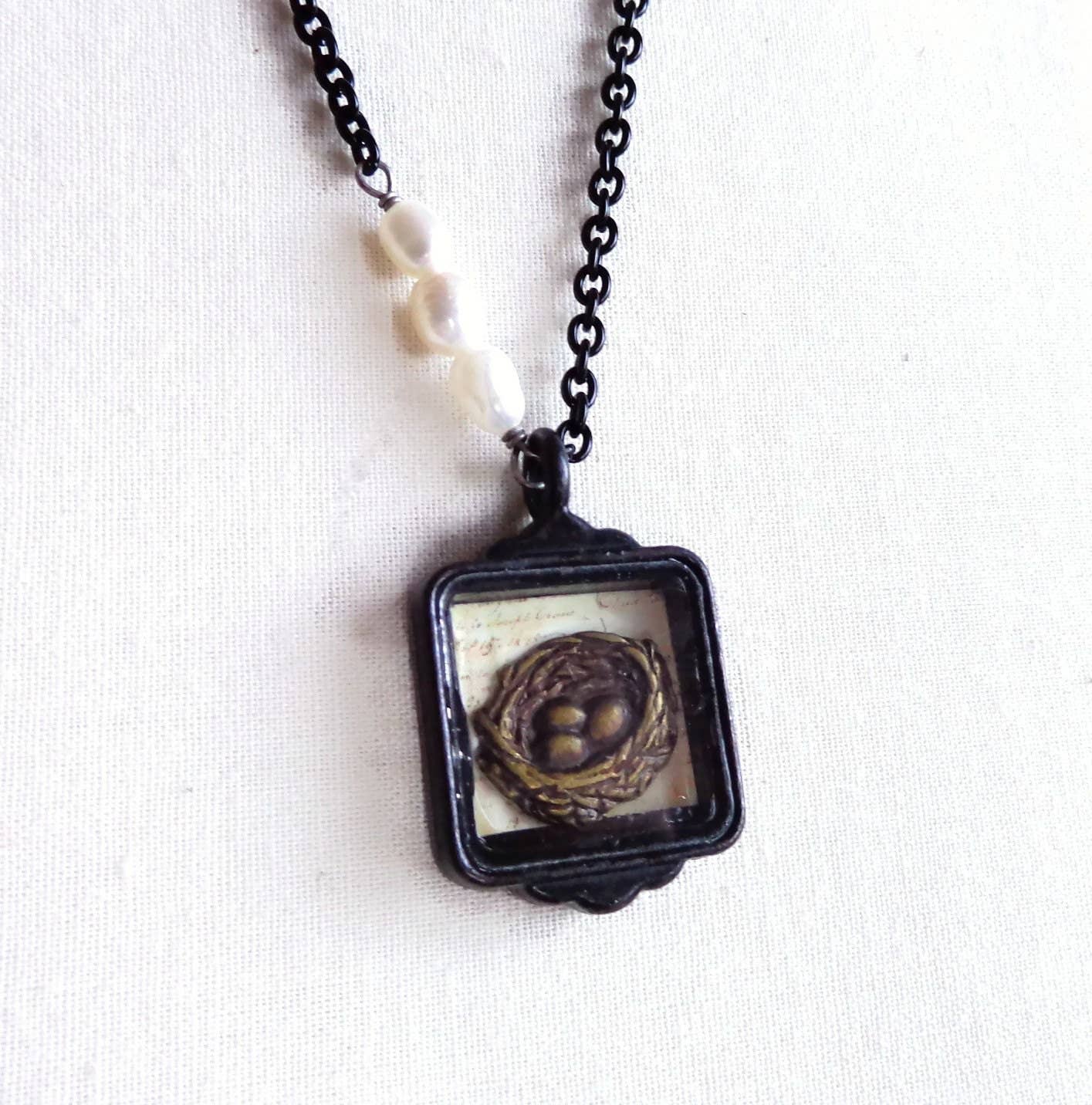 The Hallie - Bird Nest Necklace: black chain, three white pearls, square pendant with bird’s nest, available in S/M/L.