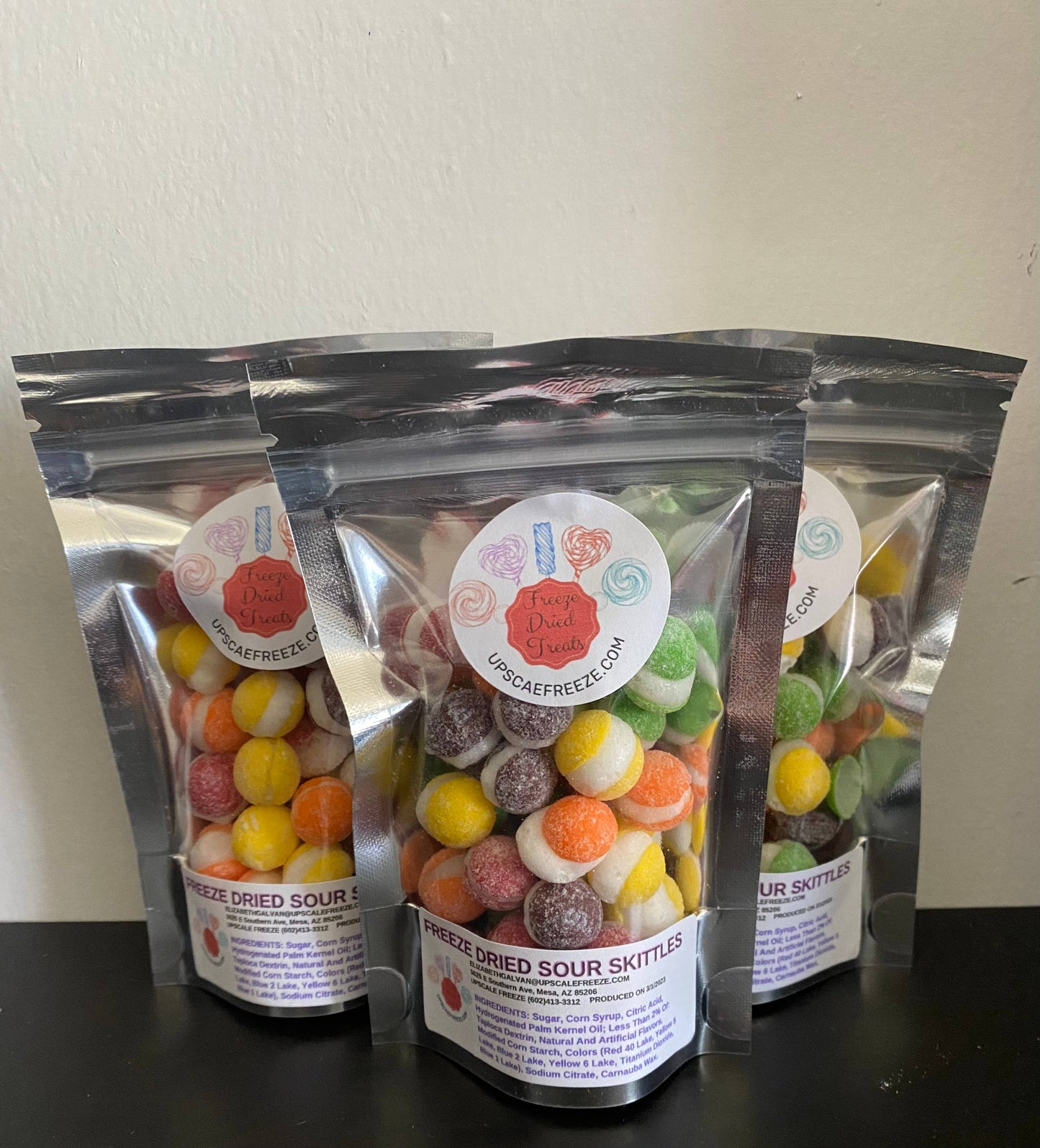 Three clear resealable bags of Freeze Dried Sour Skittles, each with a round label and upscafreezek.com. Sizes: 3oz, 6oz, 12oz.