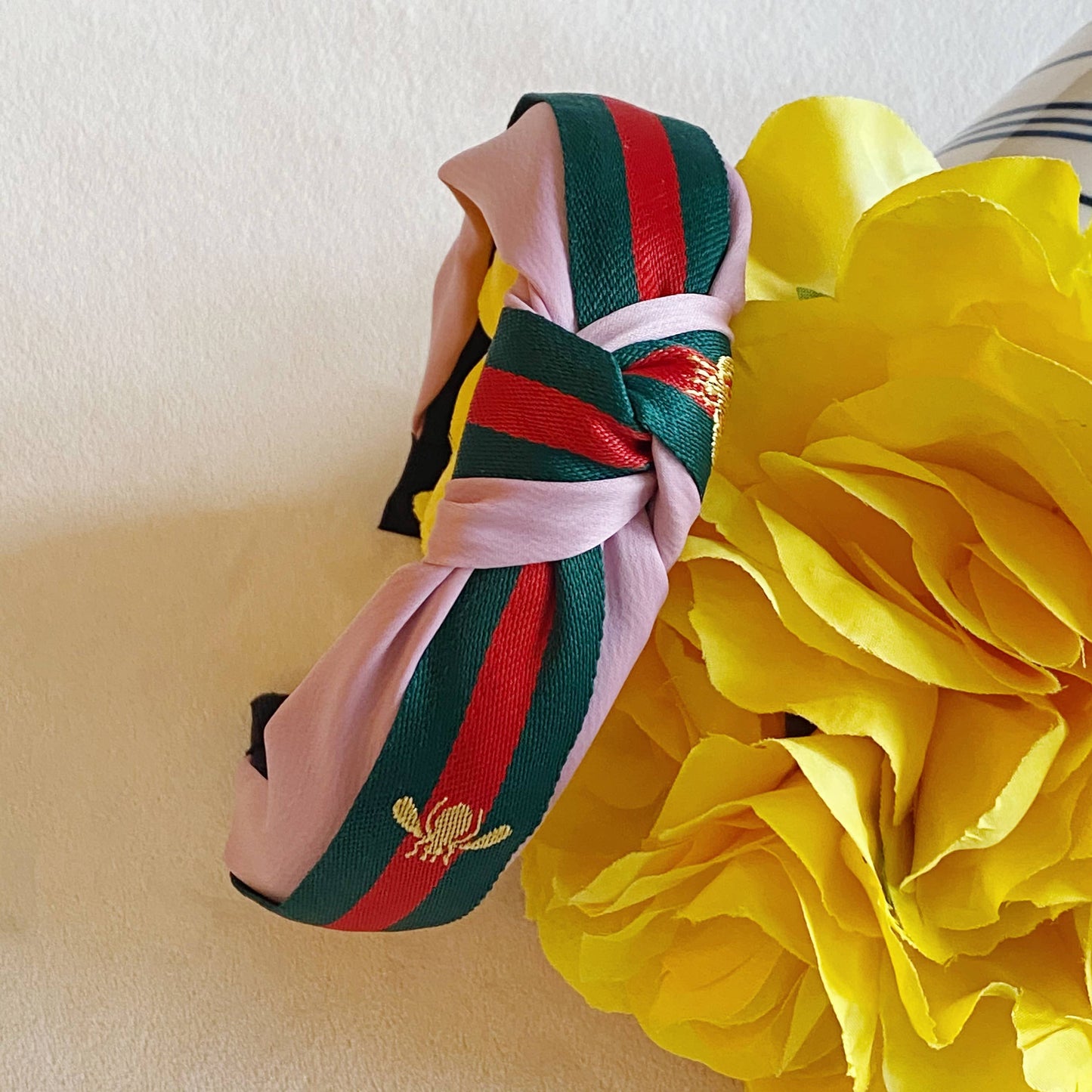 Pink knotted headband with green and red stripes, gold bee embroidery. Available in S, M, L.