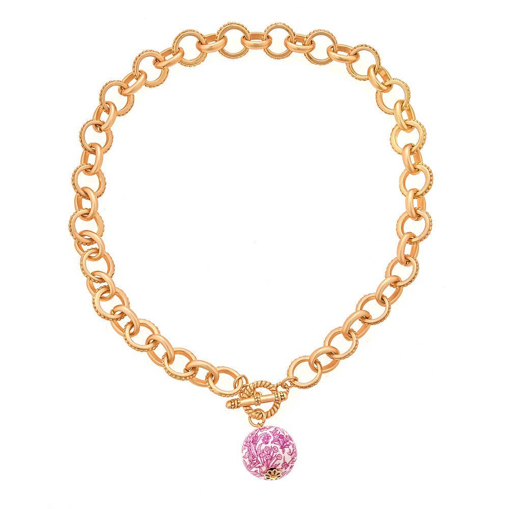 17" gold chain necklace with circular links, toggle clasp, and central pink floral-patterned bead. Available in 17".
