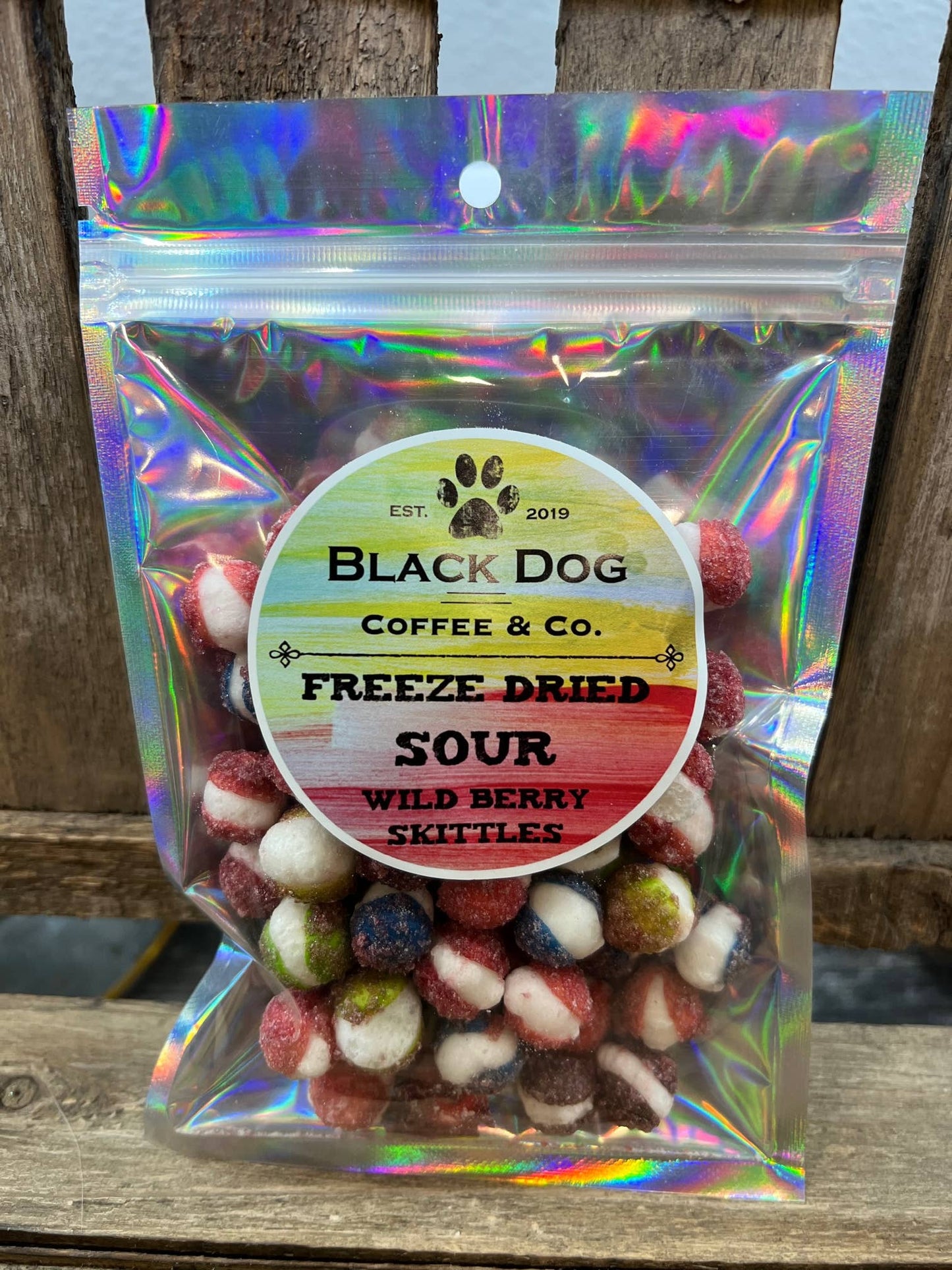 Clear, iridescent bag labeled “Freeze Dried Sour Wild Berry Skittles” with colorful freeze-dried treats; sizes: 2oz, 6oz.