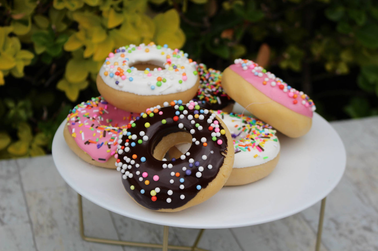 Assorted Fake Donuts with sprinkles are available. They feature a variety of designs and colors, imitating different types of popular donuts. Each set contains multiple pieces. Perfect for decor or display purposes in various settings. The size of each donut is standard, resembling the size of real donuts closely.