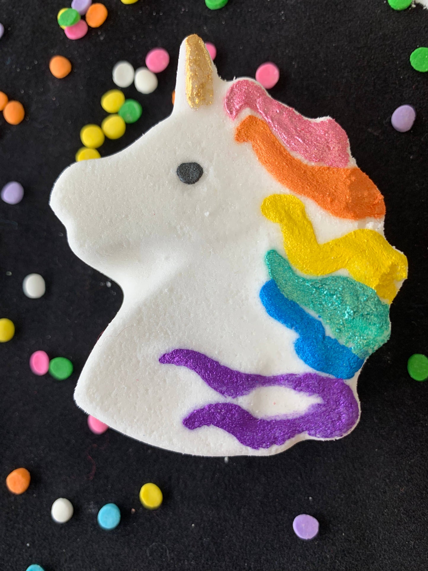 Unicorn-shaped bath bomb with rainbow mane, golden horn, and black eye. Available in 4 oz and 6 oz sizes.