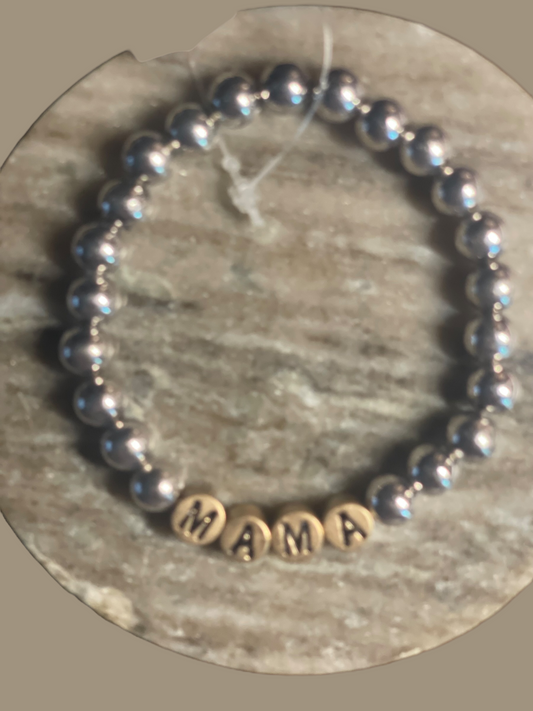 The MAMA Beaded Bracelet features metallic round beads and four light-colored beads spelling "MAMA." Available in S/M/L.