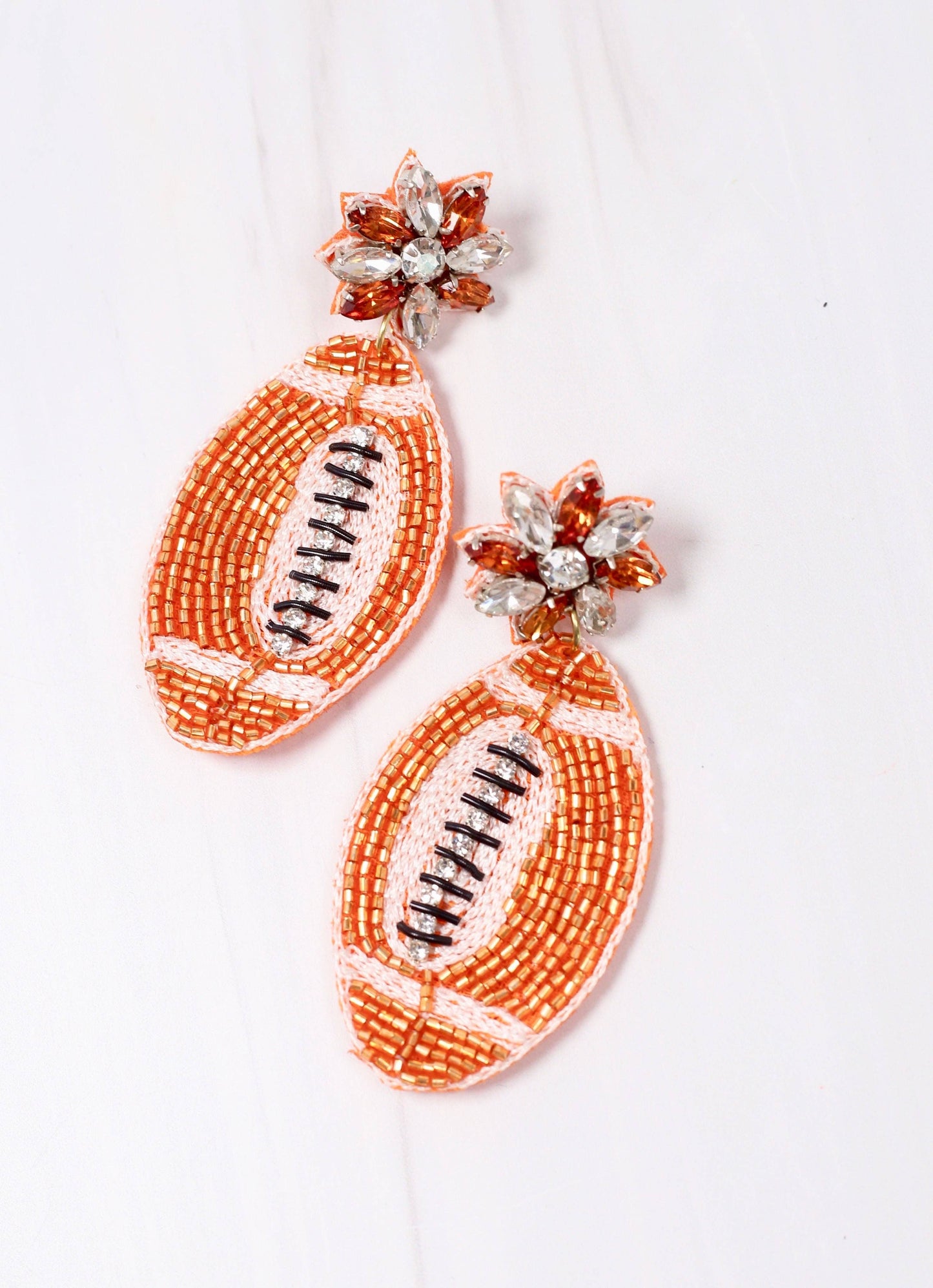 Field Goal Embellished Football Earrings—orange and white beaded footballs with gem accents. Available in one size.