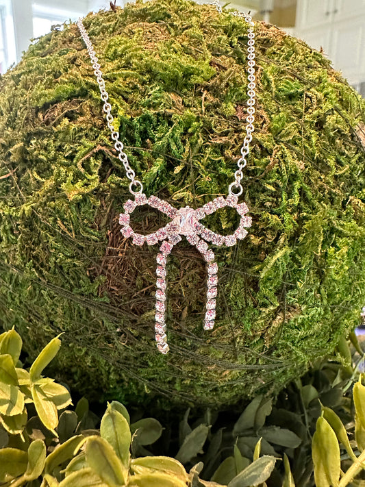 The Cutie Necklace features a sparkling pink bow-shaped pendant. Available sizes: 16", 18", and 20".