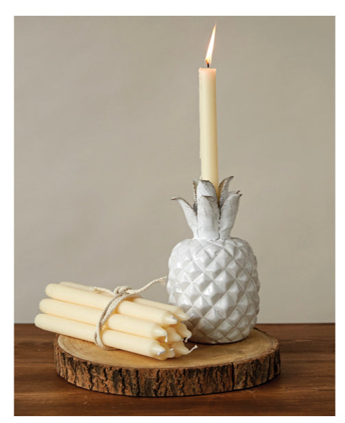 White pineapple-shaped candle holder with lit 10”H unscented taper candle. Candle available in 10” height.