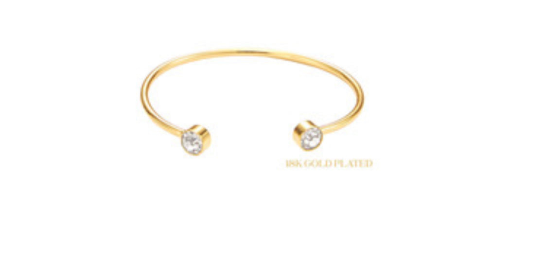 The product is an 18K Gold Plated Round Cuff featuring Clear Crystal End Accents. It is delicately designed to elegantly adorn your wrist. The cuff's size can be adjusted to fit comfortably.