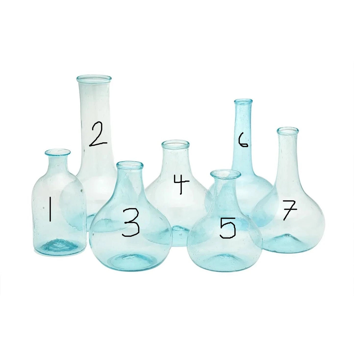 This collection consists of seven Aquamarine Bottles. Each bottle showcases a unique shape, adding diversity to the set. The bottles are crafted with a beautiful aquamarine tint, giving them a fresh, sea-glass-like appearance. Sizes of the bottles vary across the set, offering adaptability for different uses or display preferences. The product is set against and sold on a white background.