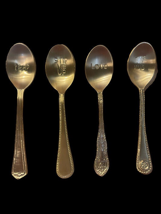 Set of four engraved brass spoons with unique handles and sayings. Sizes available. Comes in a bag.