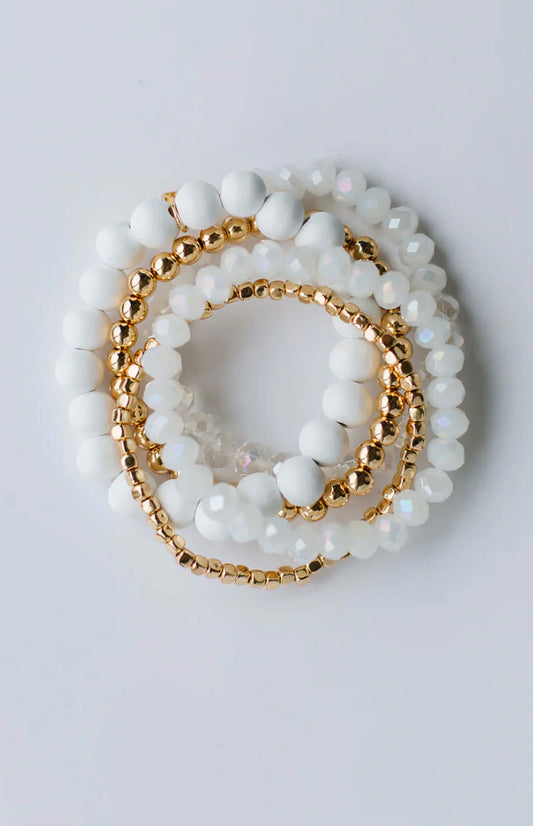 The Mandy Bracelet stack features white matte, iridescent, and shiny gold beads. Available in S/M and M/L sizes.