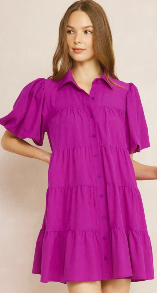 Violet Tiered Dress is designed with a button front and features a collared neckline. Short puff sleeves add a feminine touch, while the tiered ruffles bring out its playful, flirty aesthetic. The dress is available in various sizes.