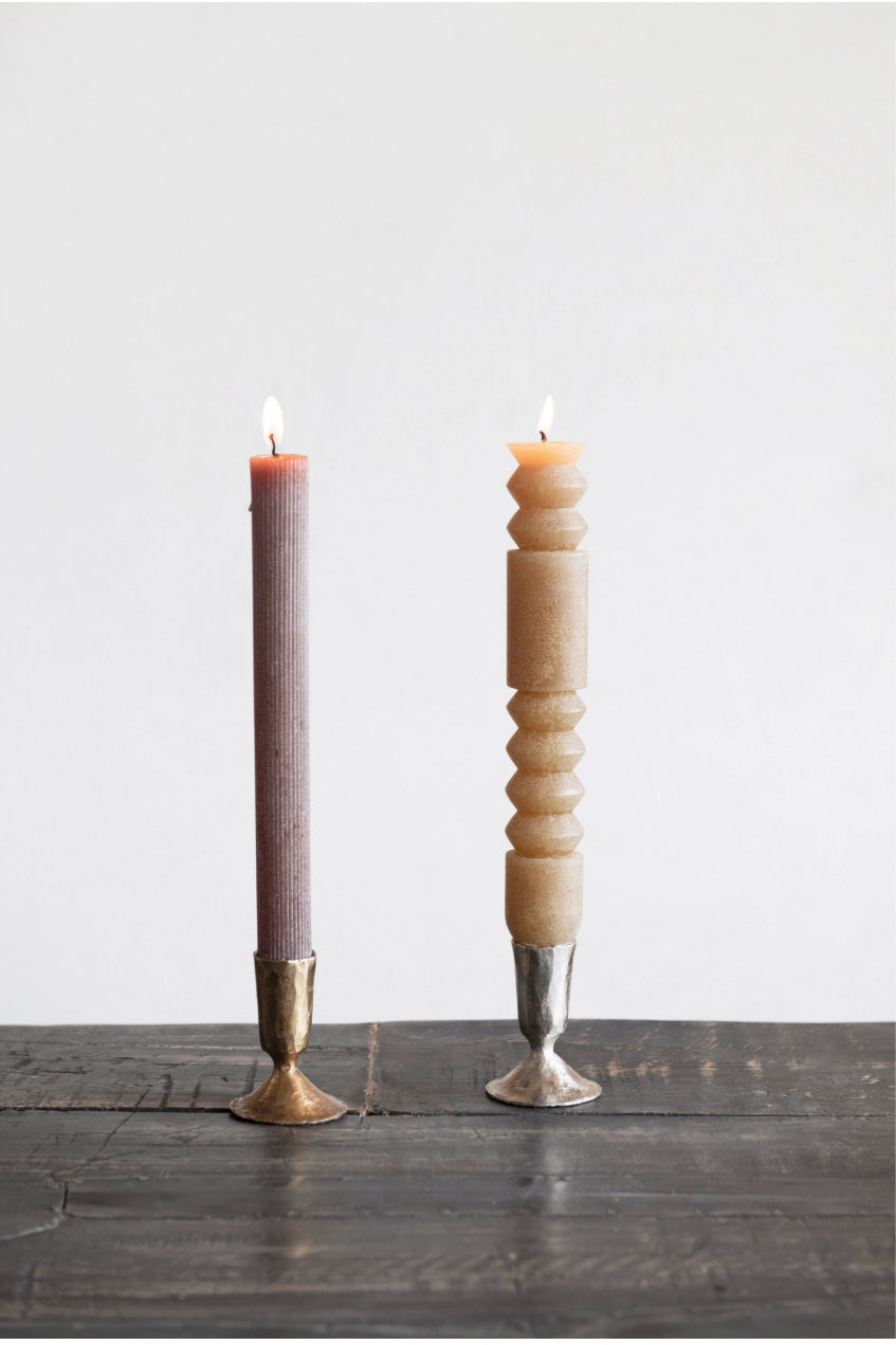 Tall mauve ribbed candle and beige geometrically-carved candle in metal taper holders. Available in 8", 10", and 12" sizes.