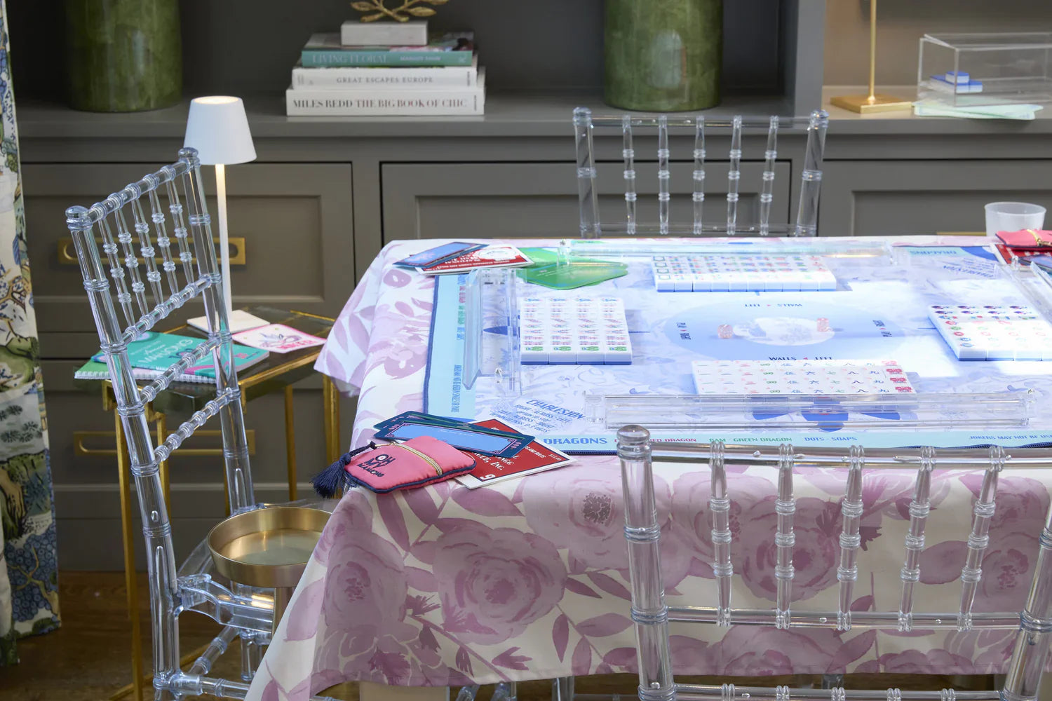 Floral tablecloth covering a table for a board game, with clear chairs around it. Available sizes: small, medium, large.