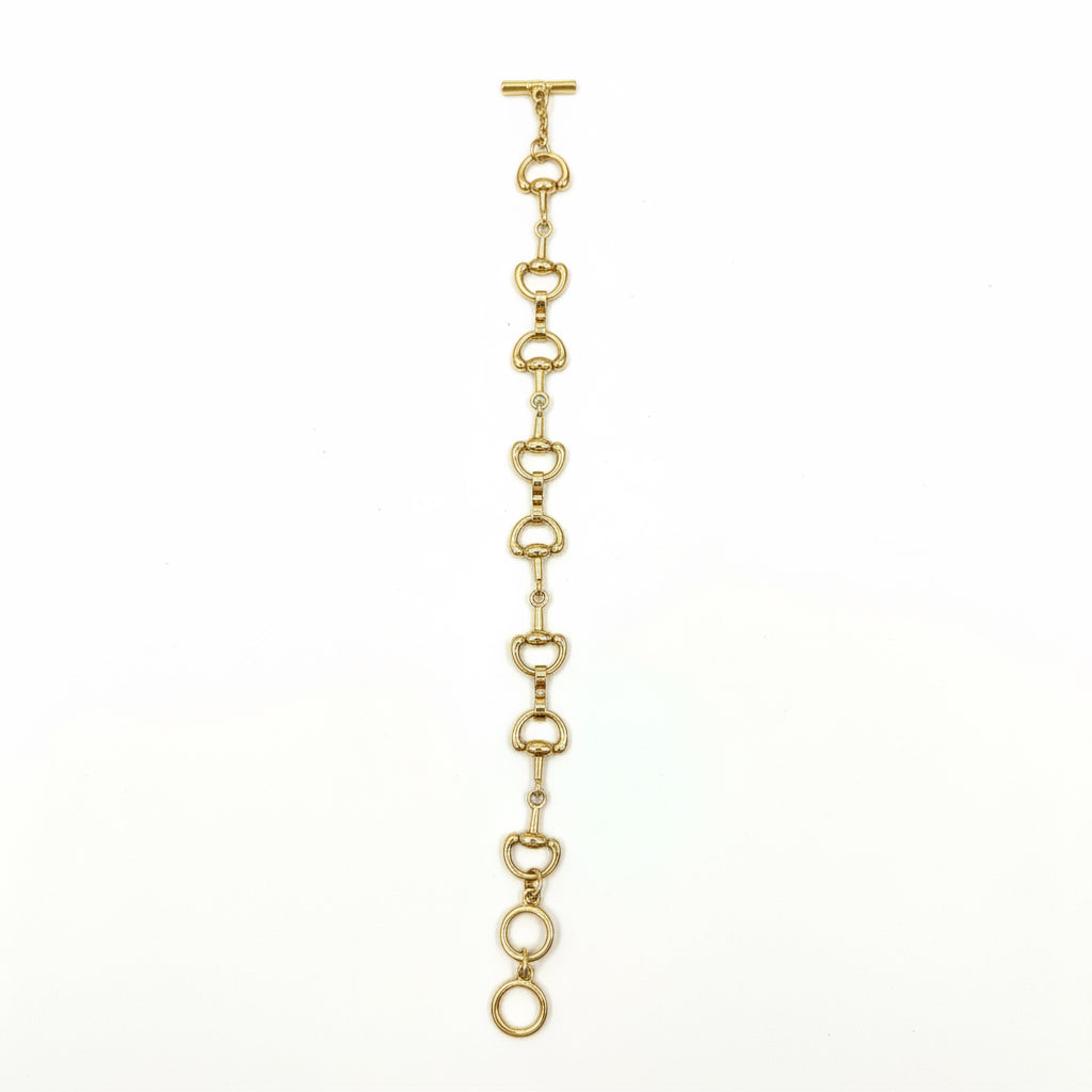 The Harry Gold Horse Bit Toggle Bracelet features linked, rounded horse bit-shaped elements in a straight line with a toggle clasp; available in multiple sizes.