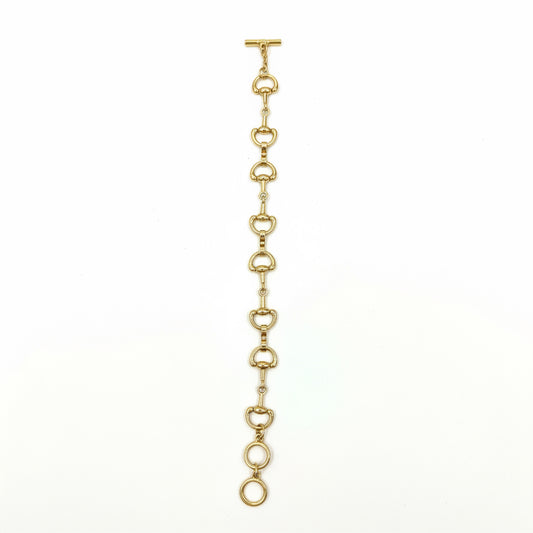 The Harry Gold Horse Bit Toggle Bracelet features linked, rounded horse bit-shaped elements in a straight line with a toggle clasp; available in multiple sizes.