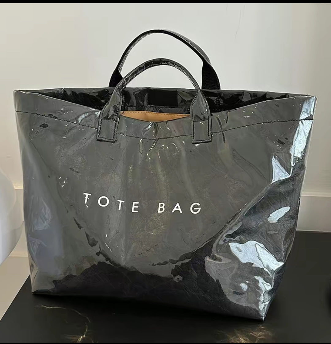 Large, shiny black Vintage Tote Bag with bold letter-print, short handles, and "TOTE BAG" in white. Available in multiple sizes.