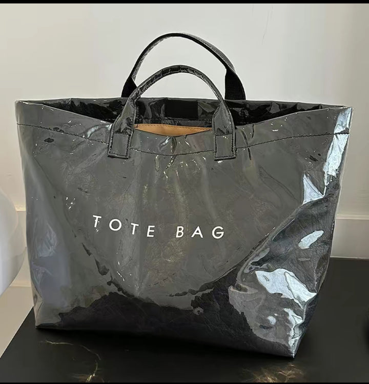Large, shiny black Vintage Tote Bag with bold letter-print, short handles, and "TOTE BAG" in white. Available in multiple sizes.