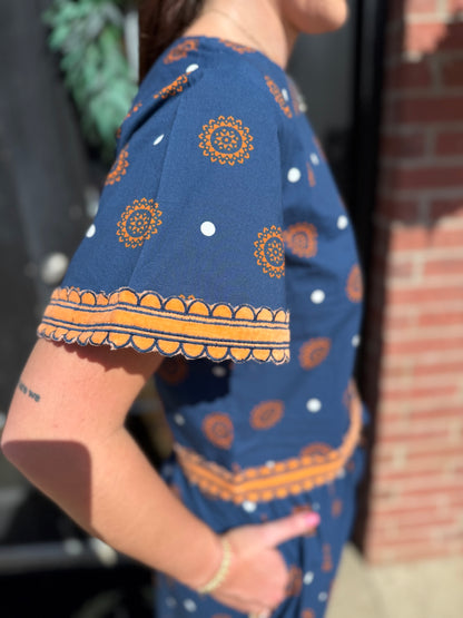 Auburn Medallion Skirt Set: striking blue two-piece with orange circular and white dot patterns, featuring intricate orange embroidery on the sleeve and waistband. Available in sizes XS–XL.