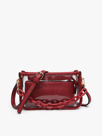 The Jessica Clear Crossbody is a red stadium-approved bag with transparent exterior, gold hardware, red chain detail, inner zippered pouch, and matching red shoulder strap. Size: 8" W x 6" H x 2.5" D.