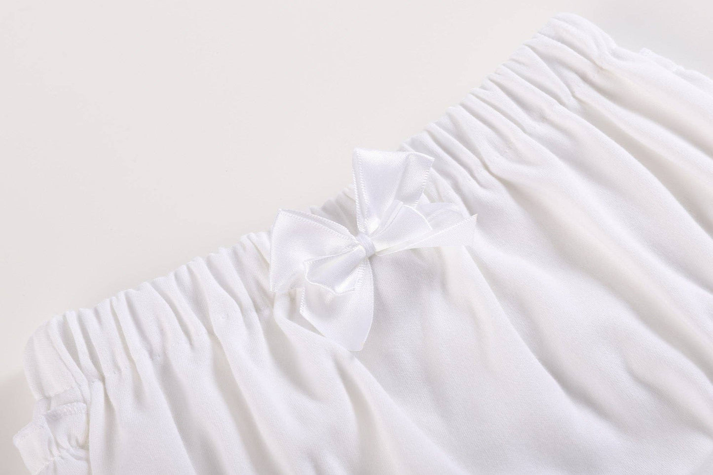 White and pink baby bloomers waistband with soft cotton, elastic band, white ruffles, satin bow. Available in size 3-6M.
