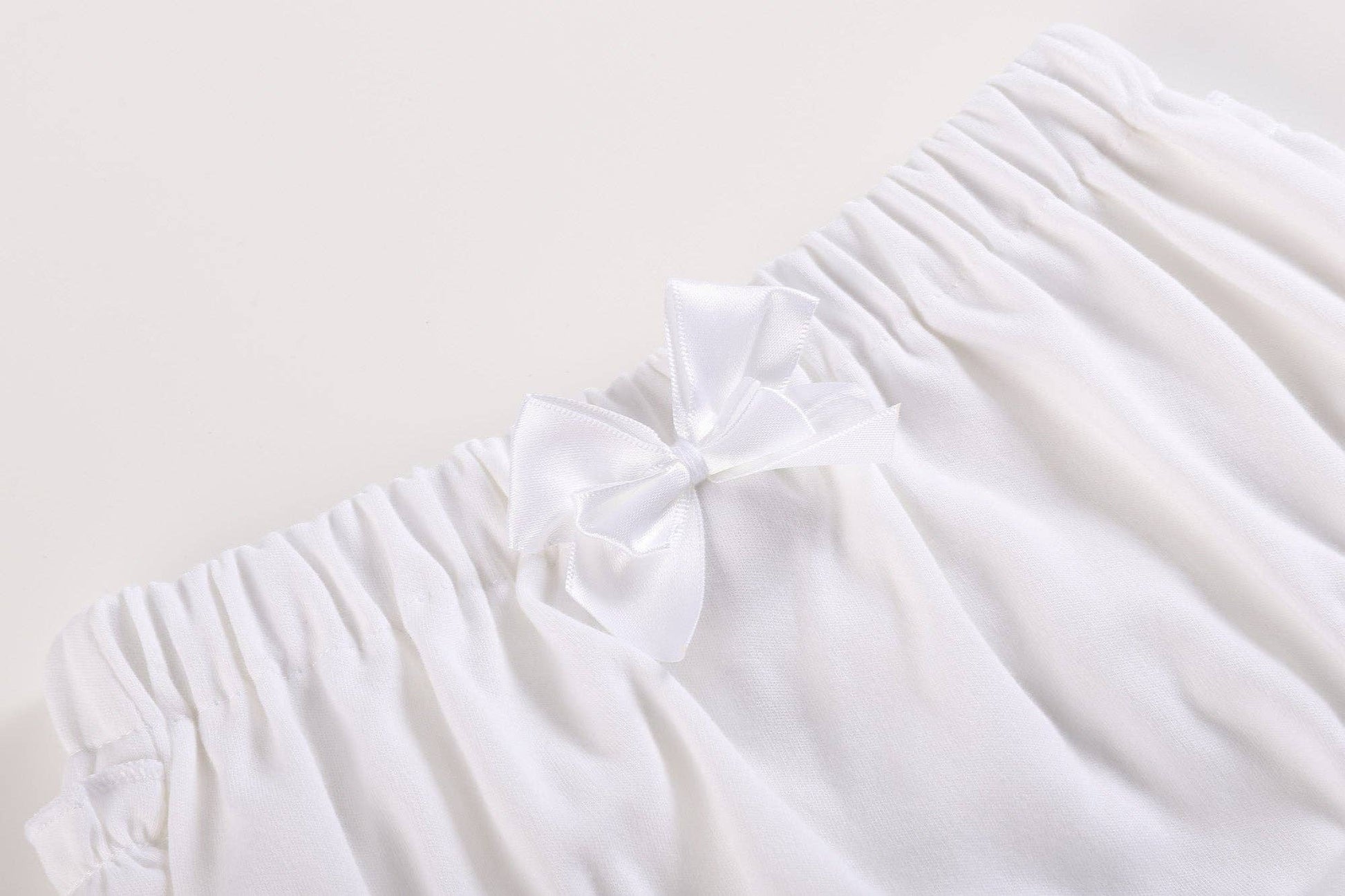 White and pink baby bloomers waistband with soft cotton, elastic band, white ruffles, satin bow. Available in size 3-6M.
