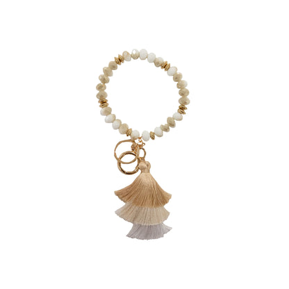Beaded bracelet keychain with white and gold beads, beige/tan/gray tassels, two gold rings. Sizes: S, M, L.
