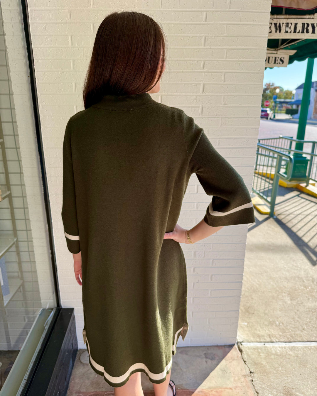 Olive green mock neck sweater dress with cream contrast trim at cuffs and hem. Available in multiple sizes.