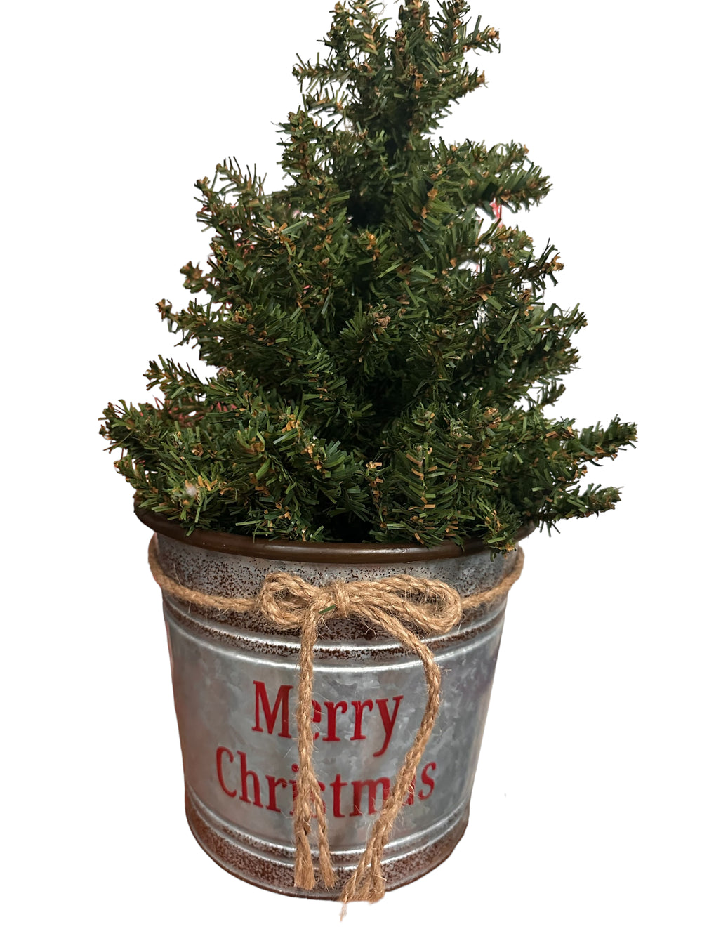 Miniature artificial Christmas tree in a galvanized metal bucket with a jute twine bow and “Merry Christmas” text.