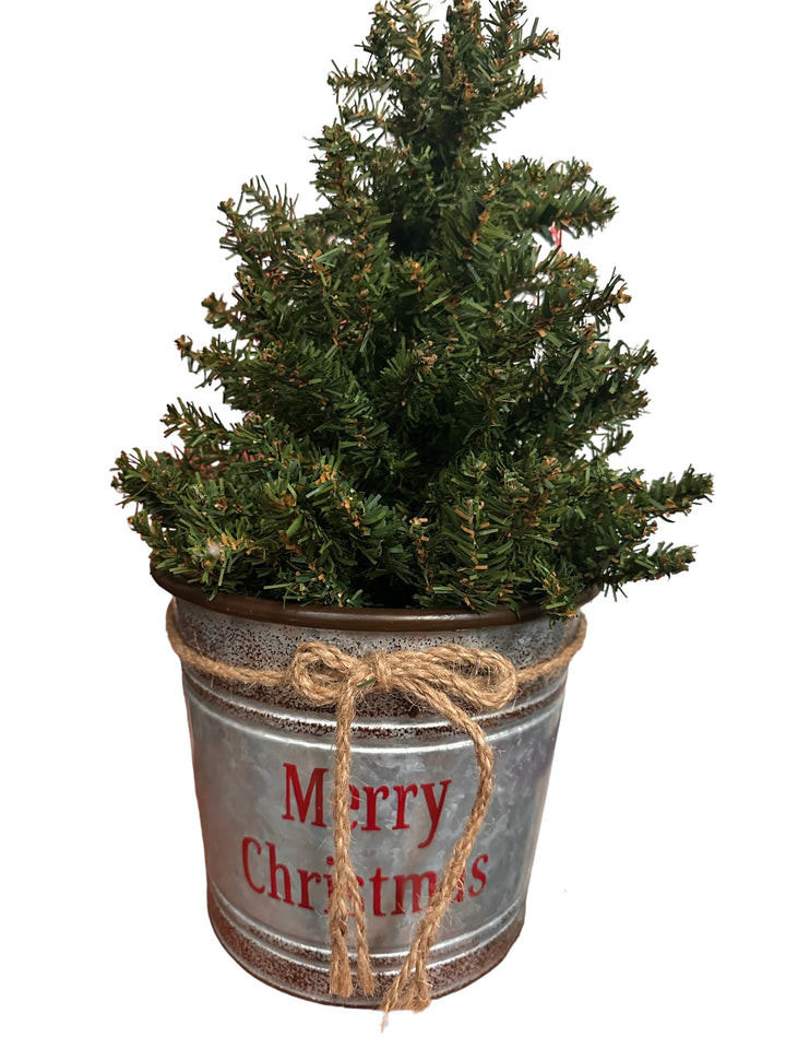 Miniature artificial Christmas tree in a galvanized metal bucket with a jute twine bow and “Merry Christmas” text.