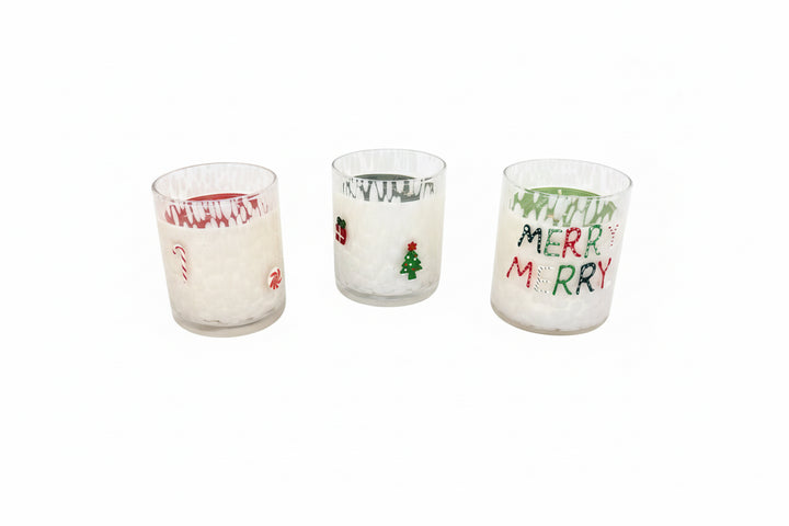 Set of three holiday soy candles in glass holders with festive designs: candy cane, Christmas tree, and “MERRY MERRY” in green and red. Available sizes: 8 oz, 16 oz.