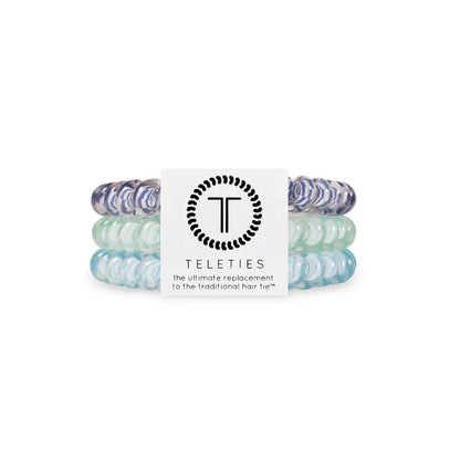Three TELETIES Hair Ties in purple, mint green, and light blue stacked together; available in small and large sizes.