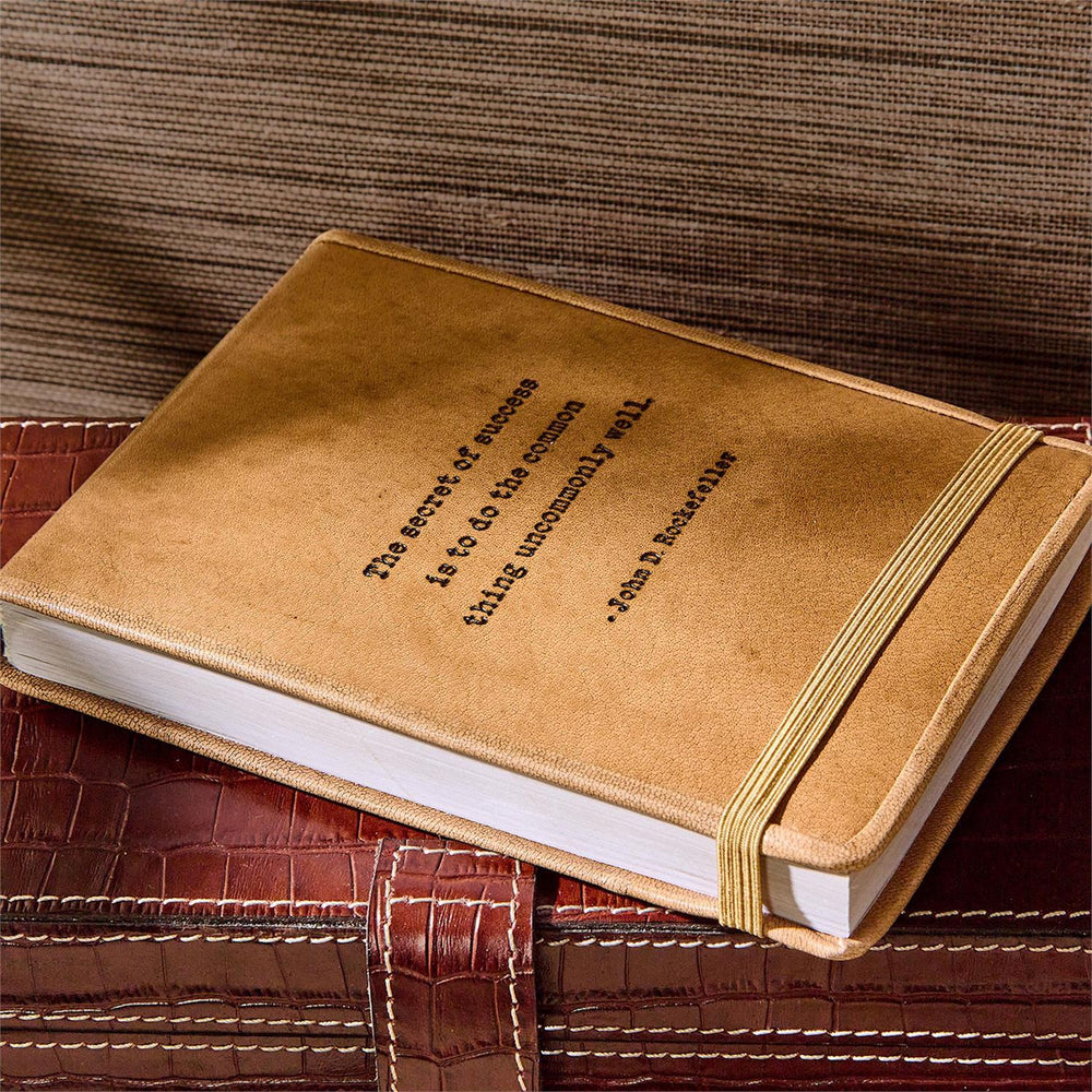 Leather Flip Notebook with elastic band, textured brown cover, embossed Rockefeller quote. Available sizes: small, medium, large.