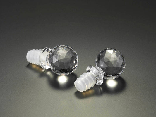 Two crystal wine stoppers with faceted, spherical tops and translucent silicone plugs. Sizes available: standard wine bottle size.