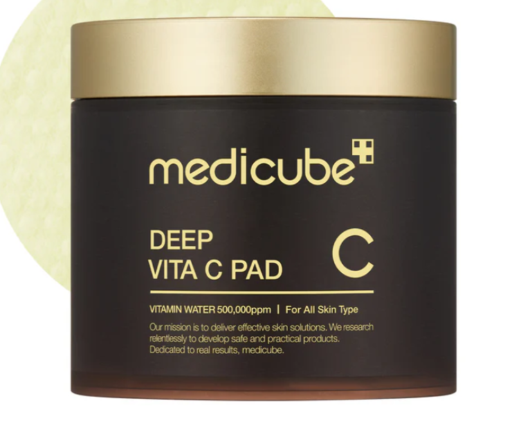 Dark brown MEDICUBE Deep Vita C Pads Brightening jar with gold lid, 70 pads per jar. Round yellow pad visible.