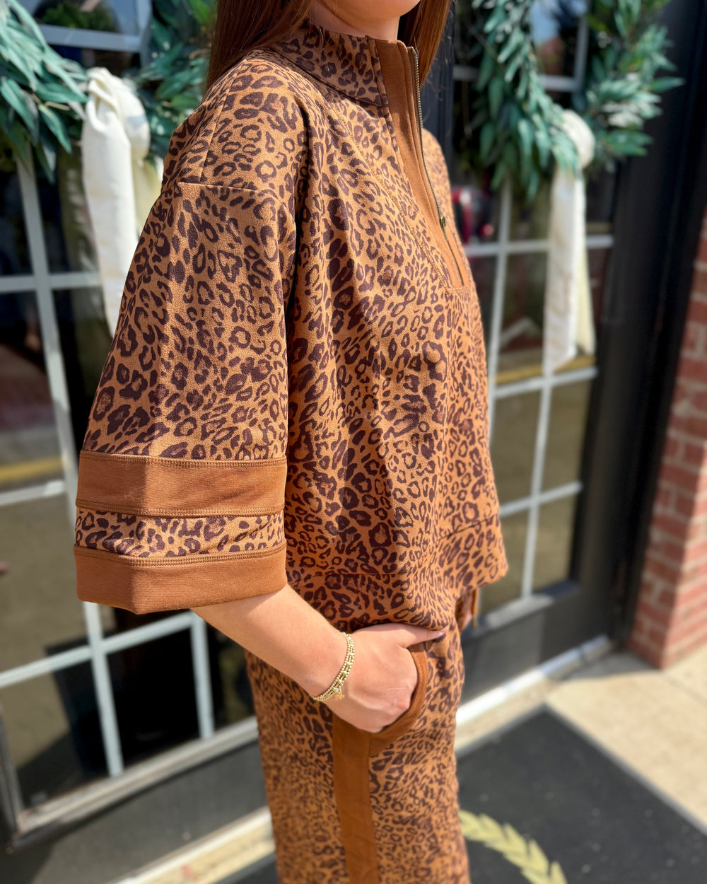 Leopard Zip-Up Top in brown and black leopard print with elbow-length sleeves and side stripes; available in sizes XS–XL.