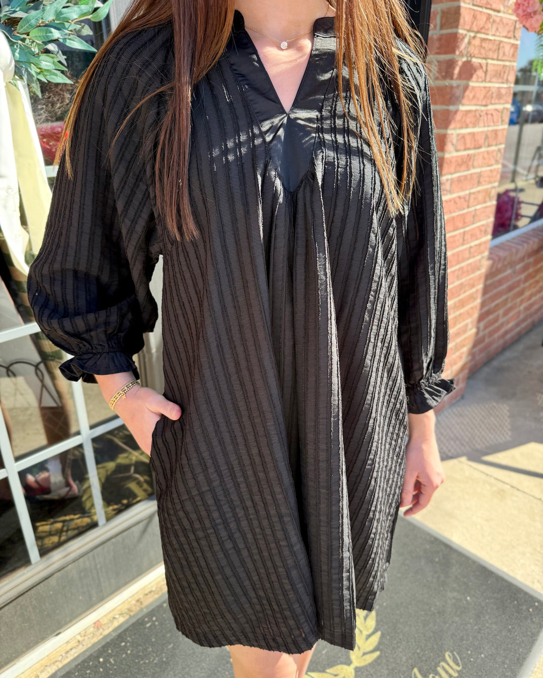 Black V-neck shift dress, long sleeves, vertical texture, side pockets.