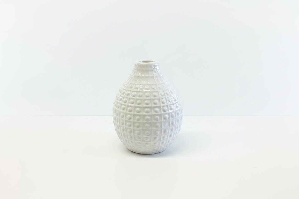 Small white ceramic vase with a narrow opening and raised grid dots. Available in multiple sizes.