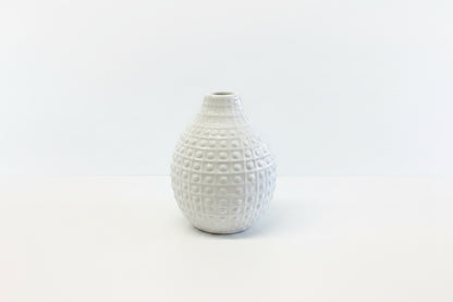 Small white ceramic vase with a narrow opening and raised grid dots. Available in multiple sizes.