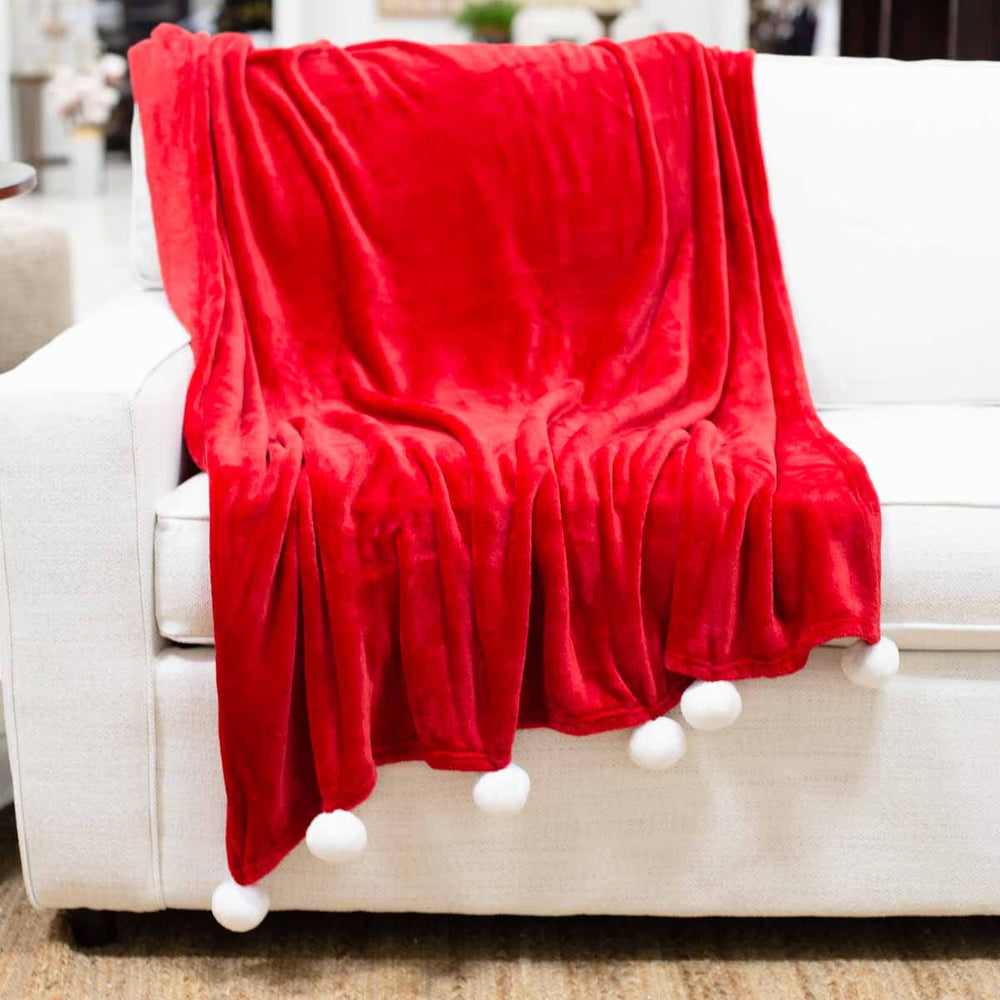 Bright red Santa pom pom throw blanket with white pom poms along the edge.