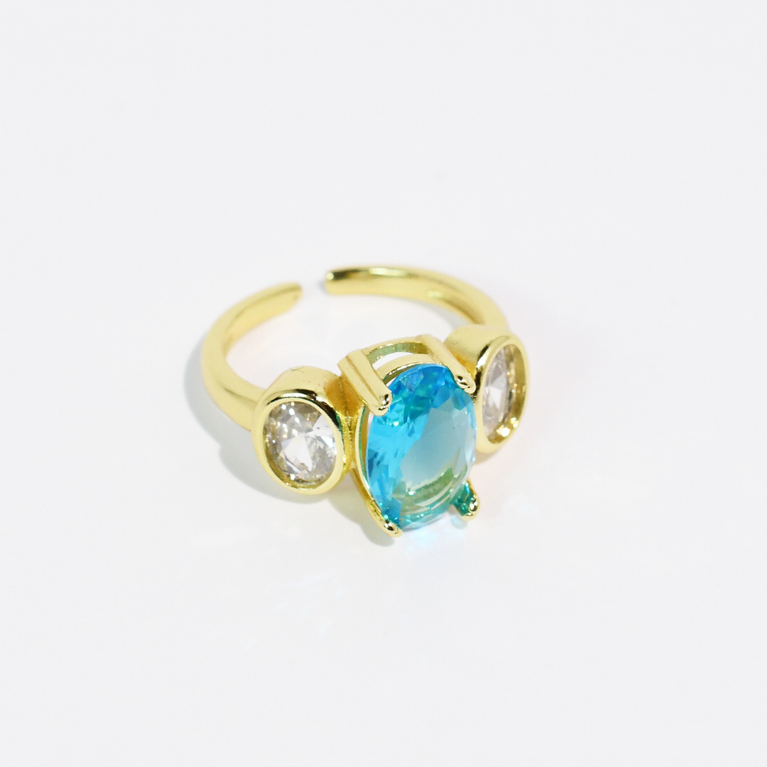 Gold ring with large oval aqua blue center stone and two small clear side stones. Available in sizes 5-9.