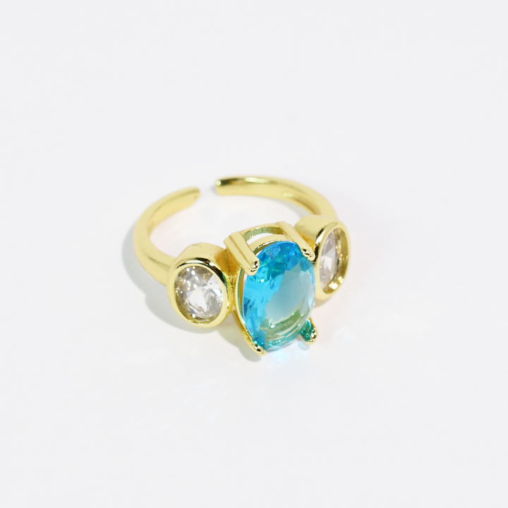Gold ring with large oval aqua blue center stone and two small clear side stones. Available in sizes 5-9.