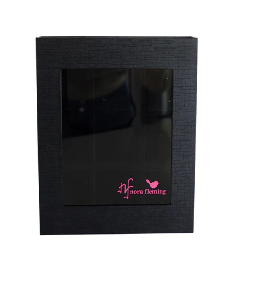 **Keepsake Box Holds 9**

A black storage box with a transparent front window. Showcases a dark interior, ideal for organizing miniatures. Features a pink "nora fleming" logo with an "nf" and bird silhouette on the lower-right corner of the window.

**Sizes Available:** Information not provided.