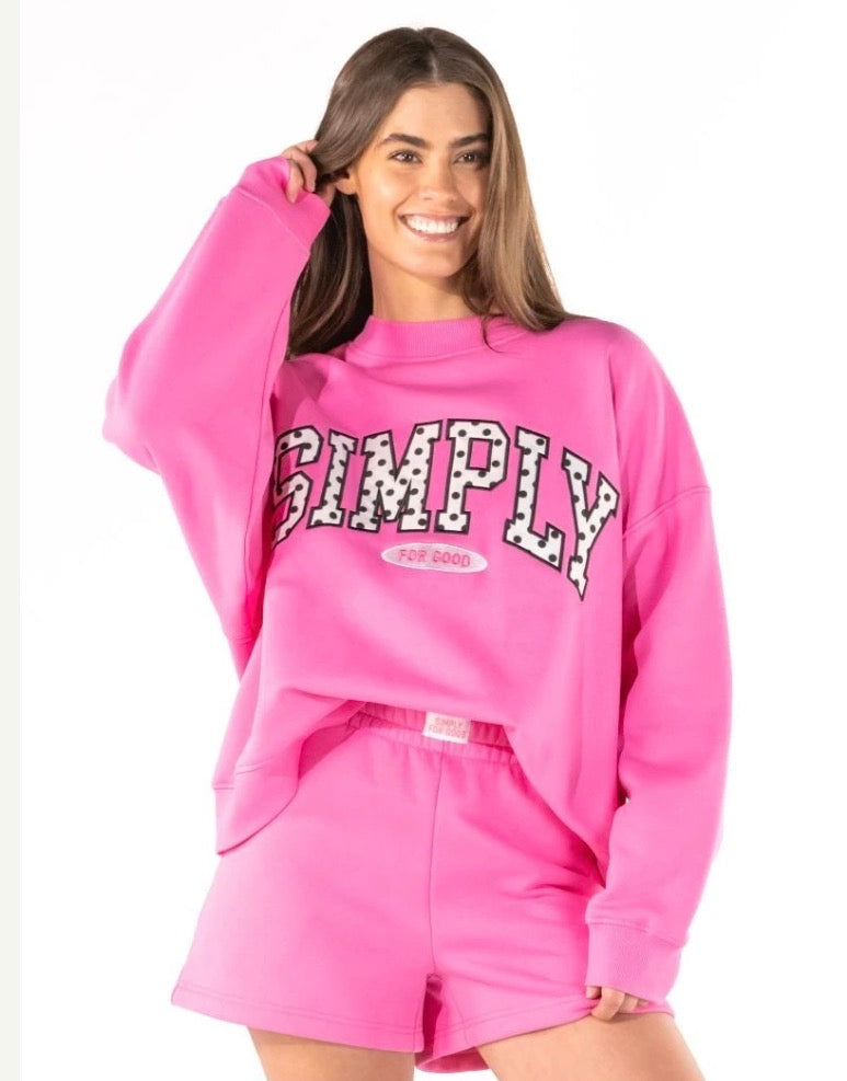 Vibrant pink, cropped Simply Polka Dot Crew Neck with “SIMPLY FOR GOOD” in bold varsity lettering; available in sizes XS–XL.