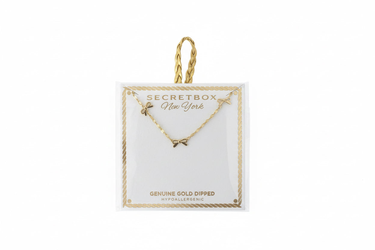 Gold Dipped Dainty Bow Station Necklace with small charms on a card, available in one size. Gold string loop at the top.