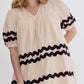 The Bay Ribbon Dress offers a chic cream color embellished with black wavy lines on the sleeves and midsection. The dress features puffed sleeves and a loose fit. Available sizes include Small, Medium, Large, and Extra-Large.